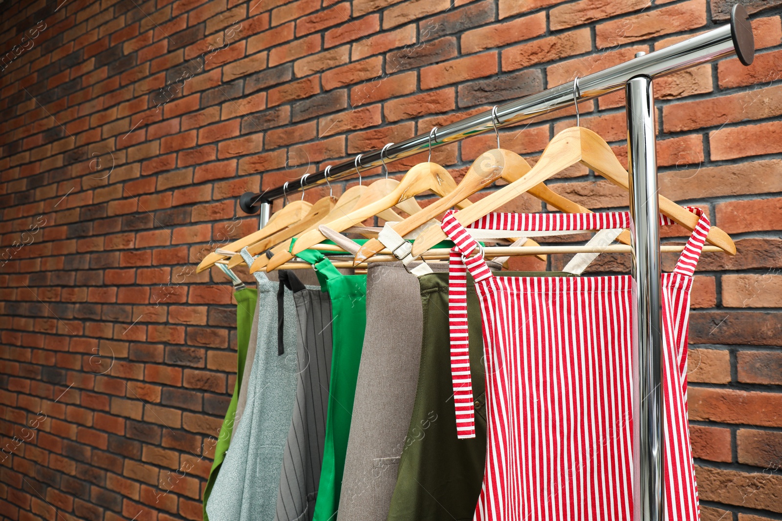 Photo of Many chef's aprons hanging on brick wall