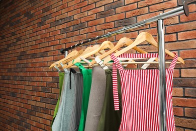 Photo of Many chef's aprons hanging on brick wall