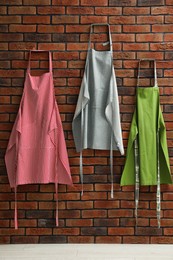 Photo of Many chef's aprons hanging on brick wall