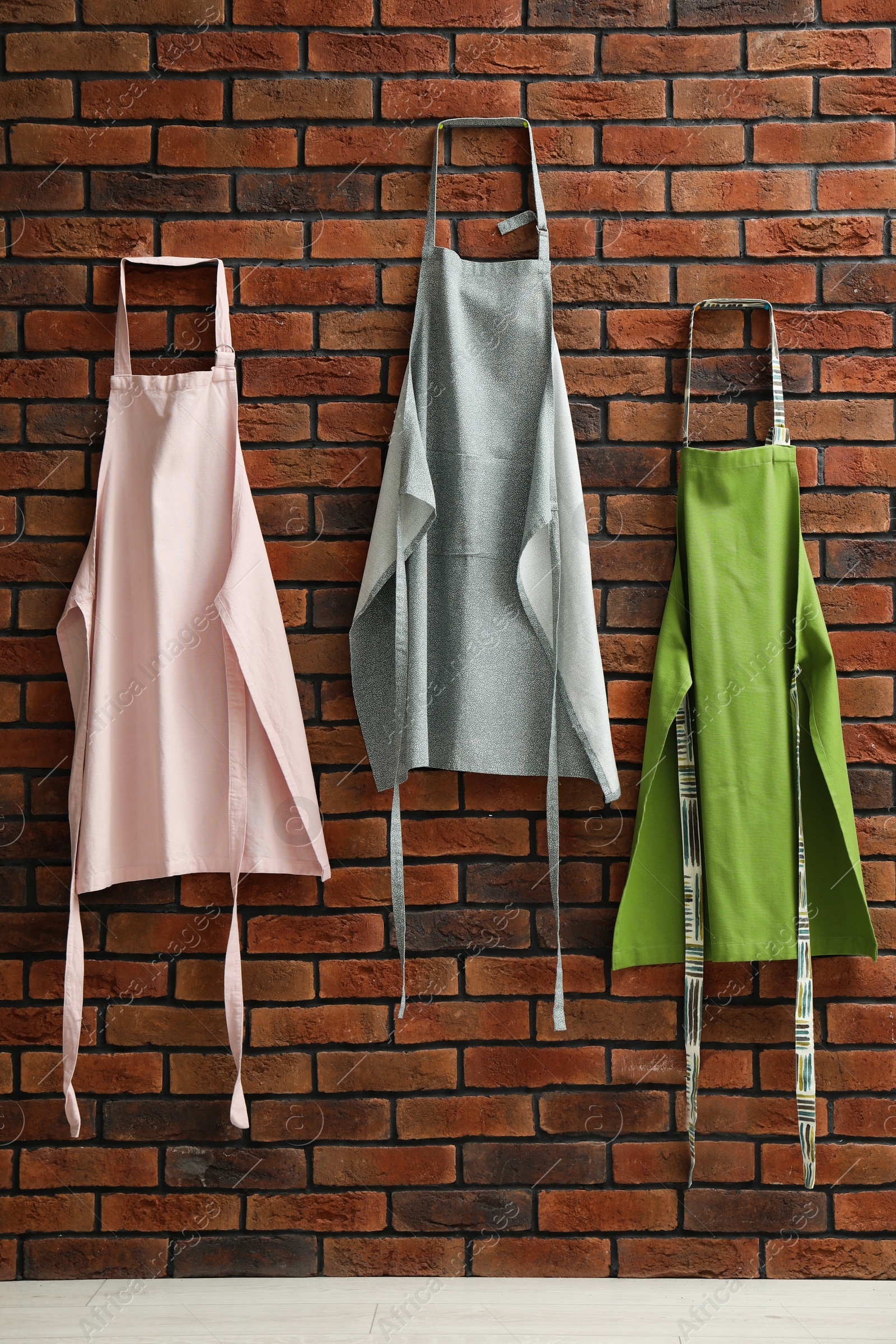 Photo of Many chef's aprons hanging on brick wall