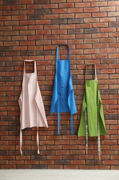 Photo of Many chef's aprons hanging on brick wall