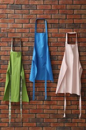 Photo of Many chef's aprons hanging on brick wall