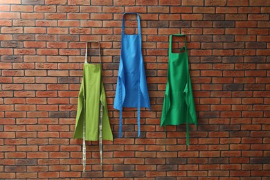 Photo of Many chef's aprons hanging on brick wall