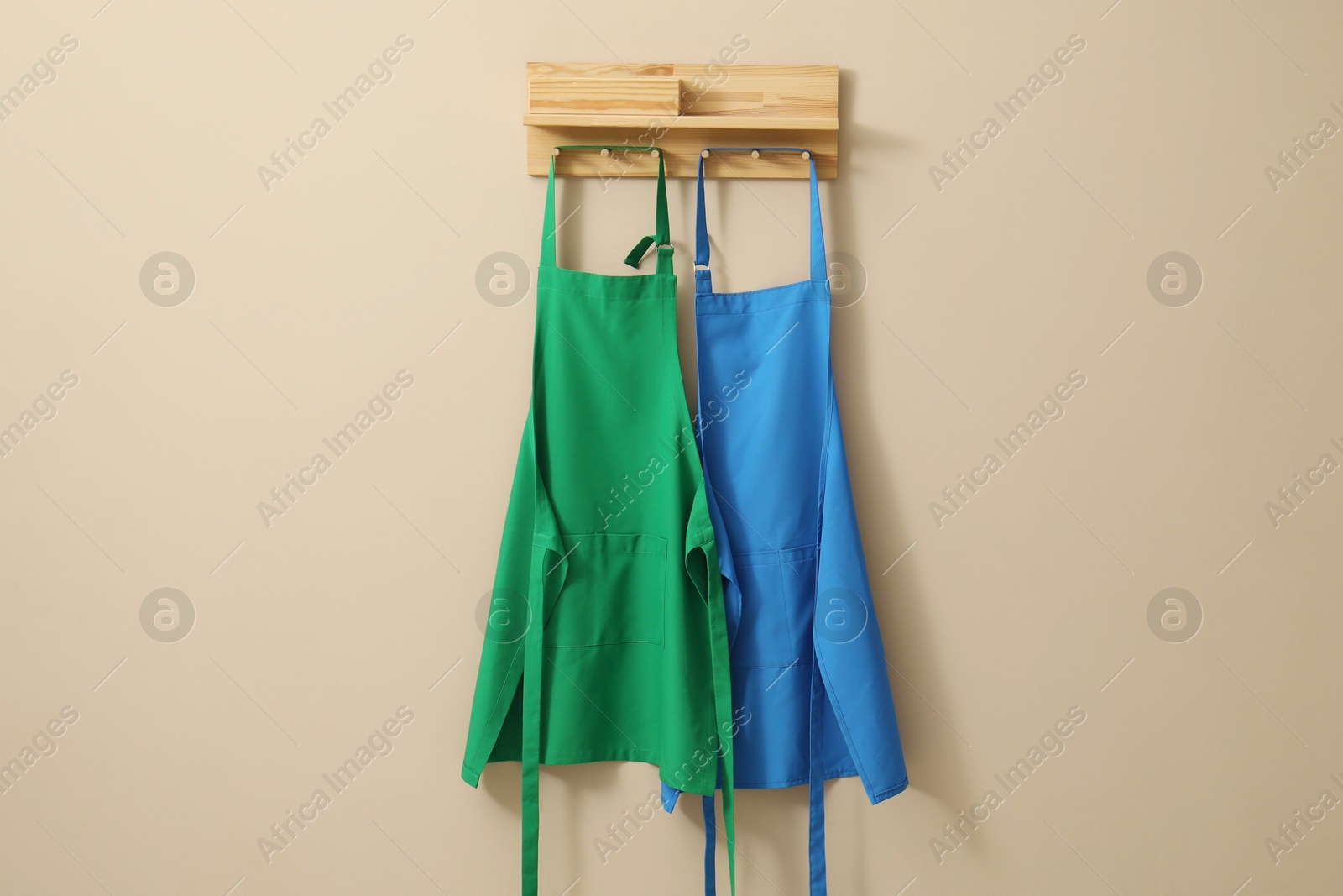 Photo of Two chef's aprons hanging on beige wall