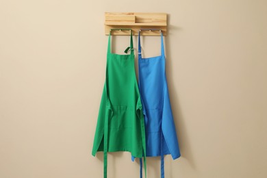 Photo of Two chef's aprons hanging on beige wall