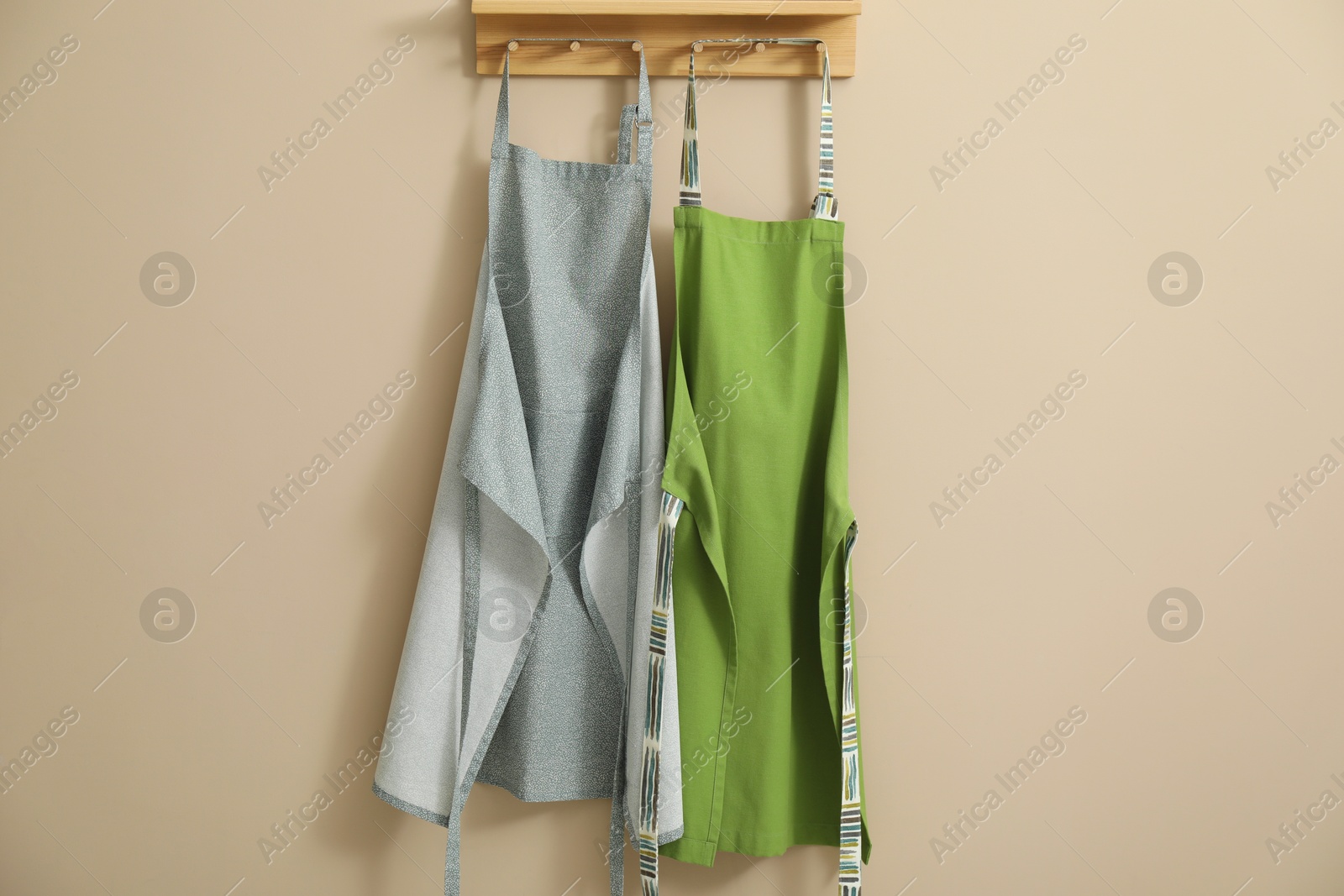 Photo of Two chef's aprons hanging on beige wall