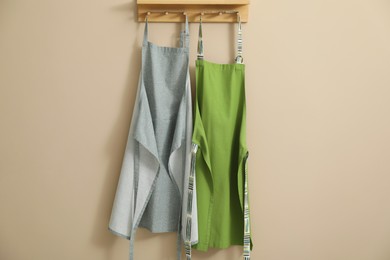 Two chef's aprons hanging on beige wall