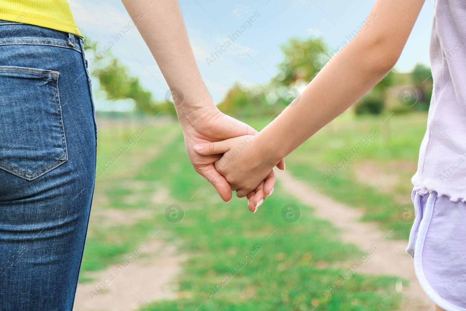 Photo of Mother and daughter holding hands outdoors, closeup