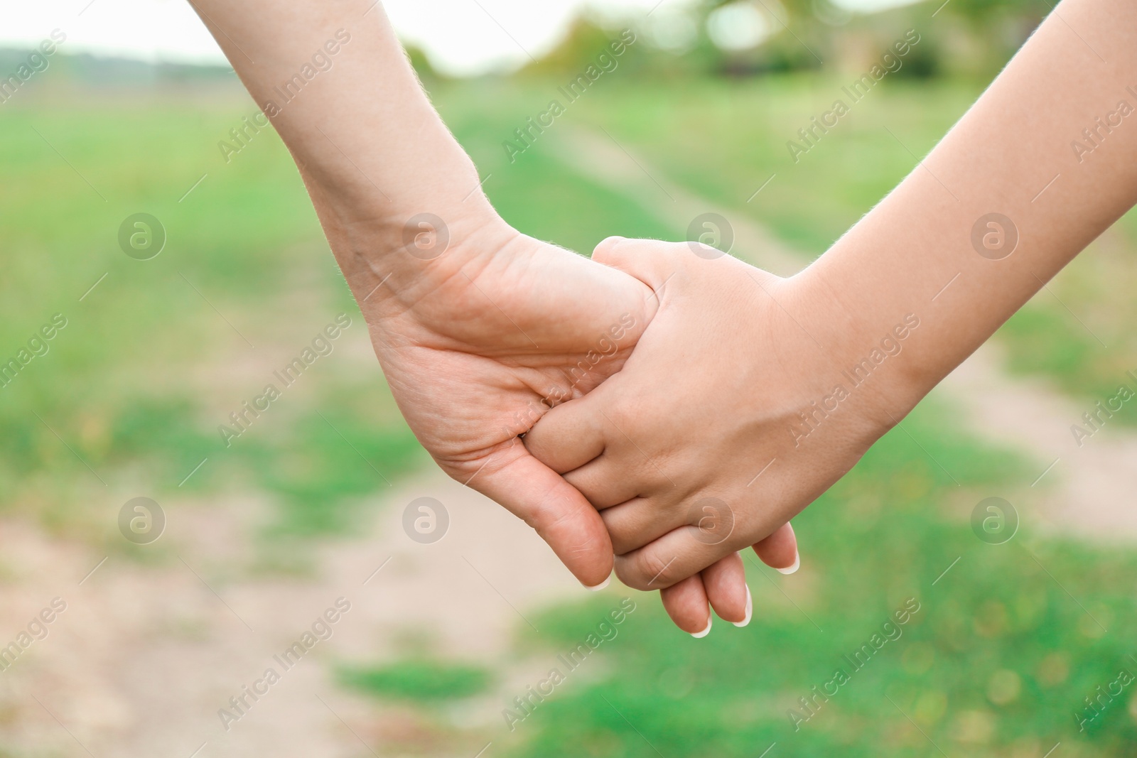 Photo of Mother and son holding hands outdoors, closeup