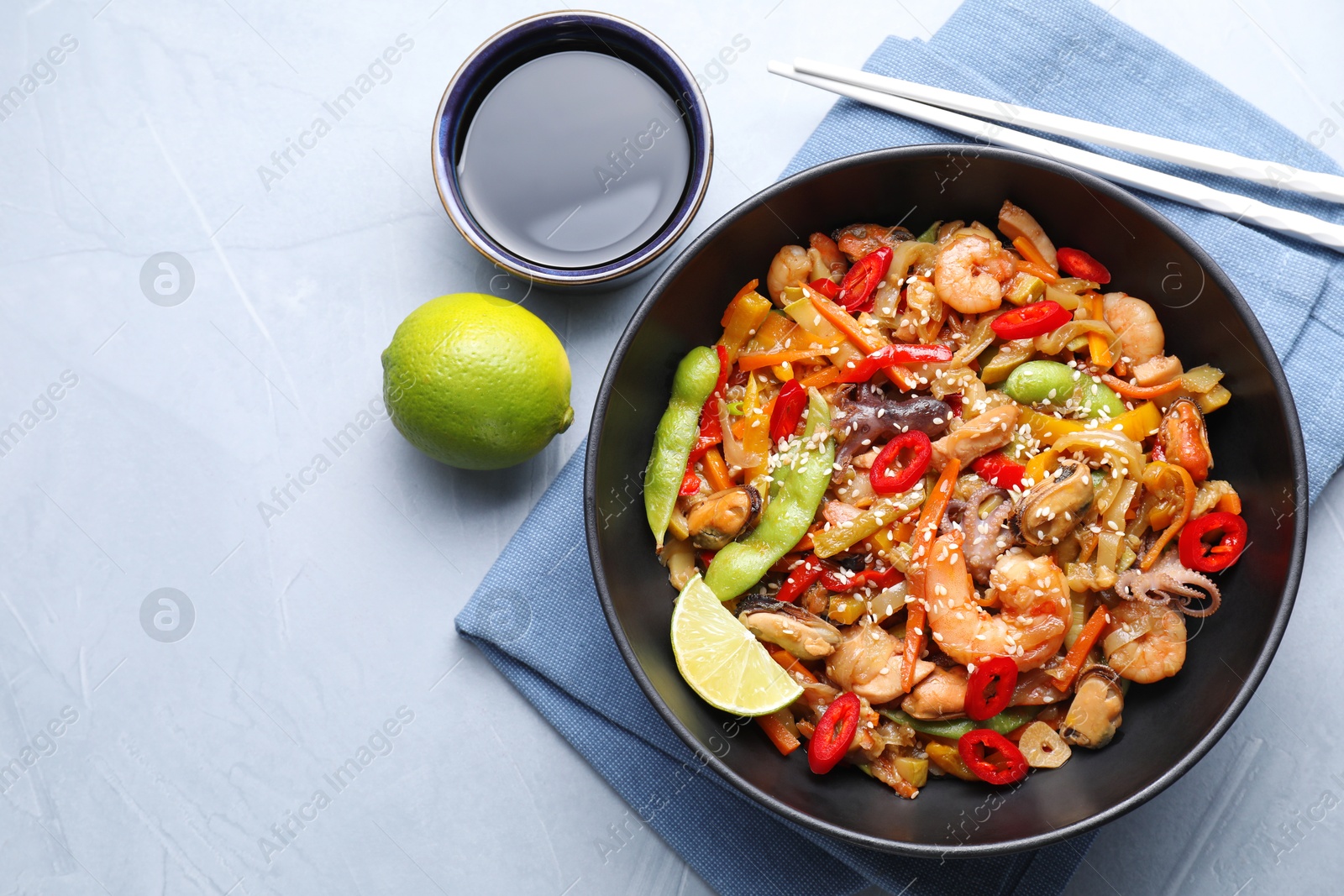 Photo of Stir-fry sea food served on light grey table, flat lay