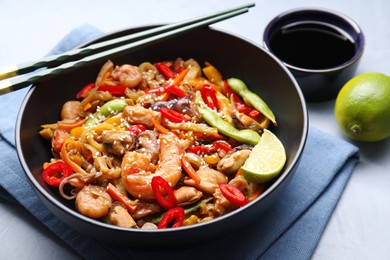 Photo of Stir-fry sea food served on light grey table, closeup