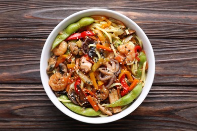 Photo of Stir-fry noodles with sea food in bowl on wooden table, top view