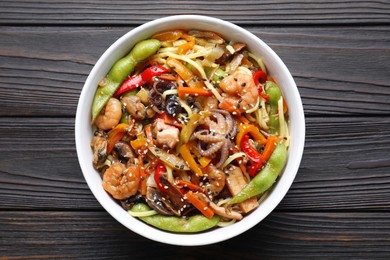 Photo of Stir-fry noodles with sea food in bowl on wooden table, top view