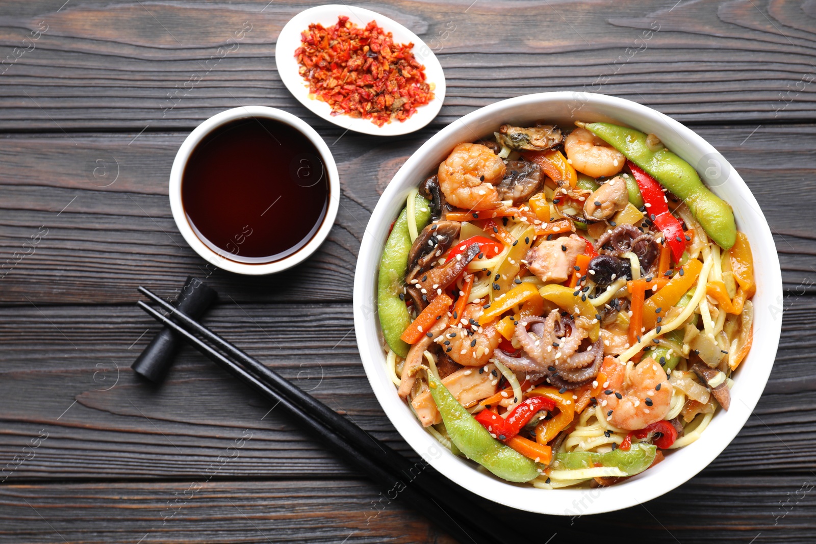 Photo of Stir-fry noodles with sea food served on wooden table, flat lay