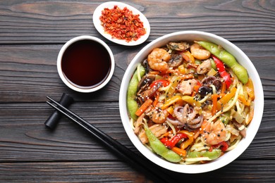 Photo of Stir-fry noodles with sea food served on wooden table, flat lay