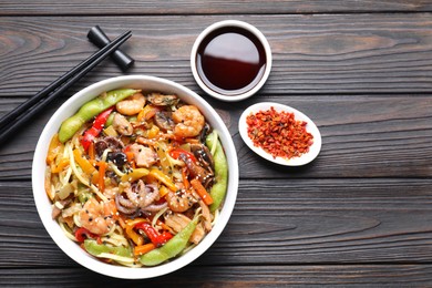 Photo of Stir-fry noodles with sea food served on wooden table, flat lay