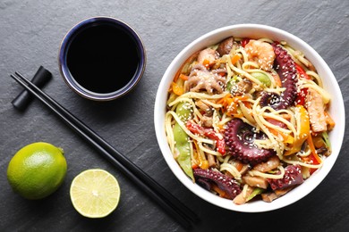 Stir-fry noodles with sea food served on grey textured table, flat lay