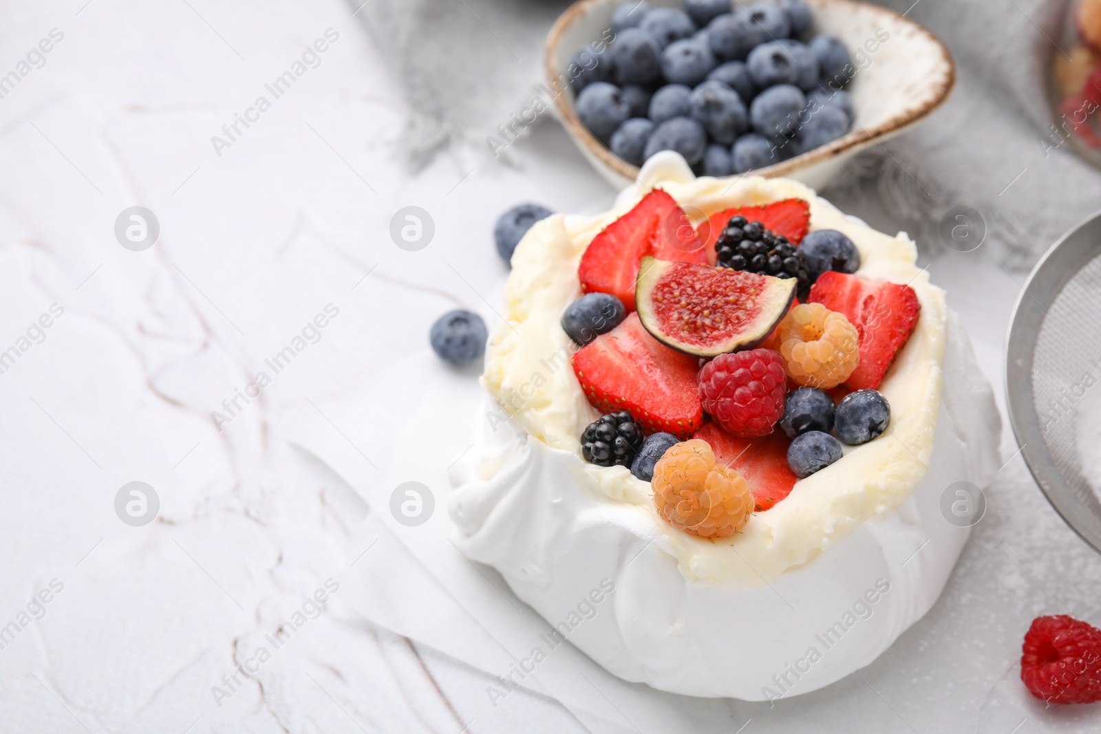 Photo of Pavlova cake (meringue dessert) with whipped cream, fresh berries and fig on white table, closeup. Space for text