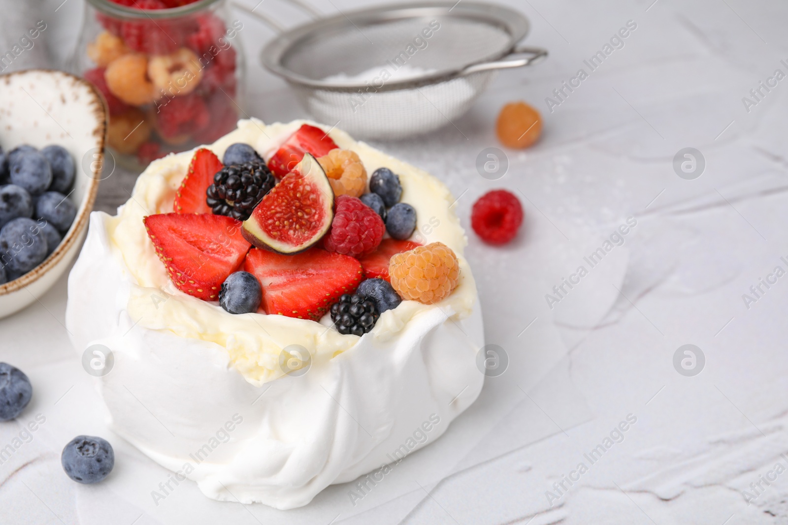 Photo of Pavlova cake (meringue dessert) with whipped cream, fresh berries and fig on white table, closeup. Space for text