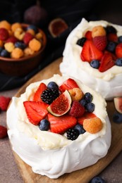 Photo of Pavlova cake (meringue dessert) with whipped cream, fresh berries and fig on table, closeup