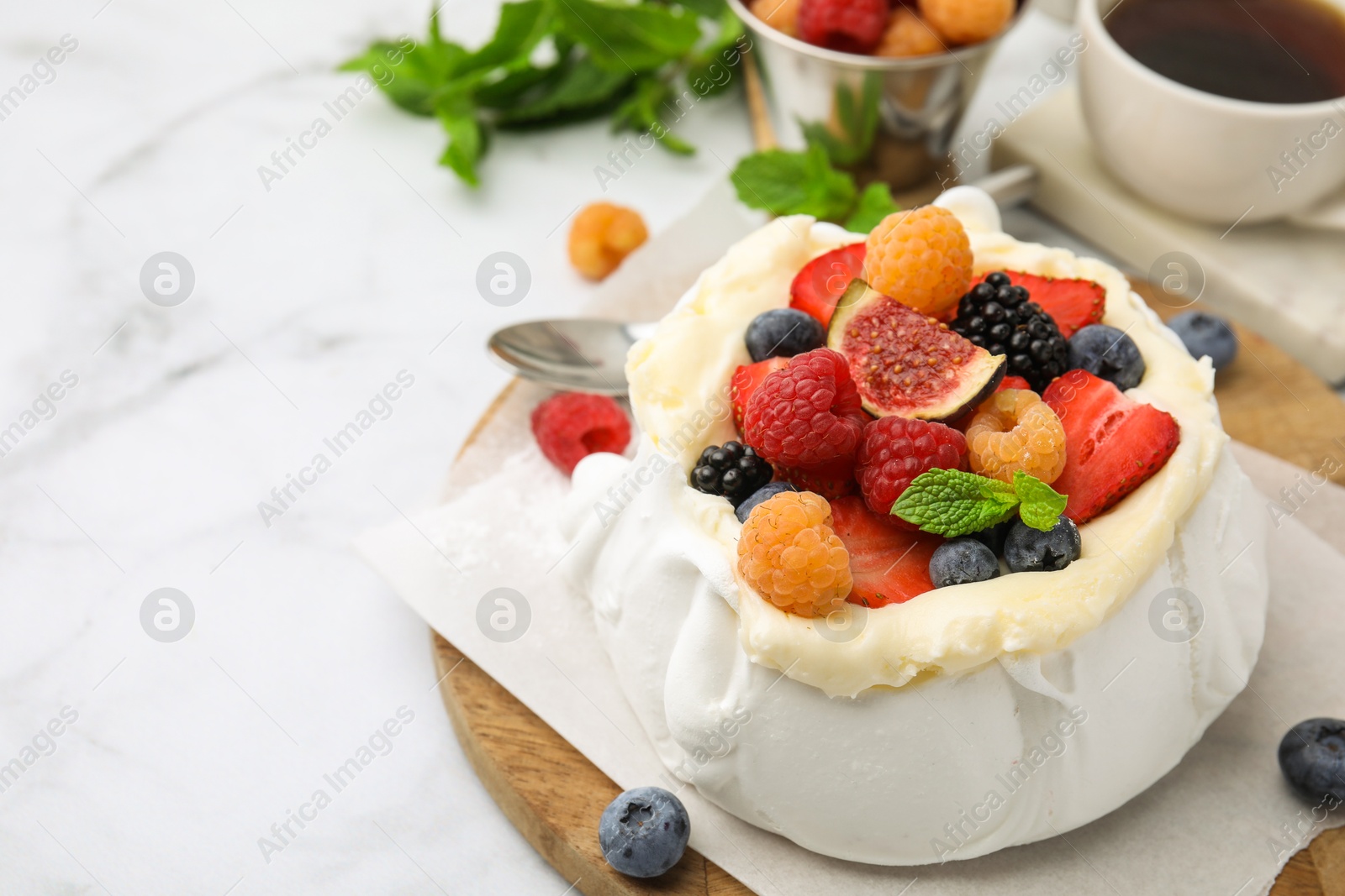 Photo of Pavlova cake (meringue dessert) with whipped cream, fresh berries, fig and mint on white marble table, closeup