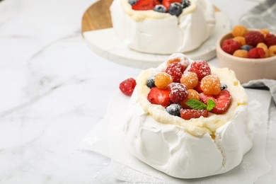 Photo of Pavlova cake (meringue dessert) with whipped cream, fresh berries, powdered sugar and mint on white marble table, closeup. Space for text