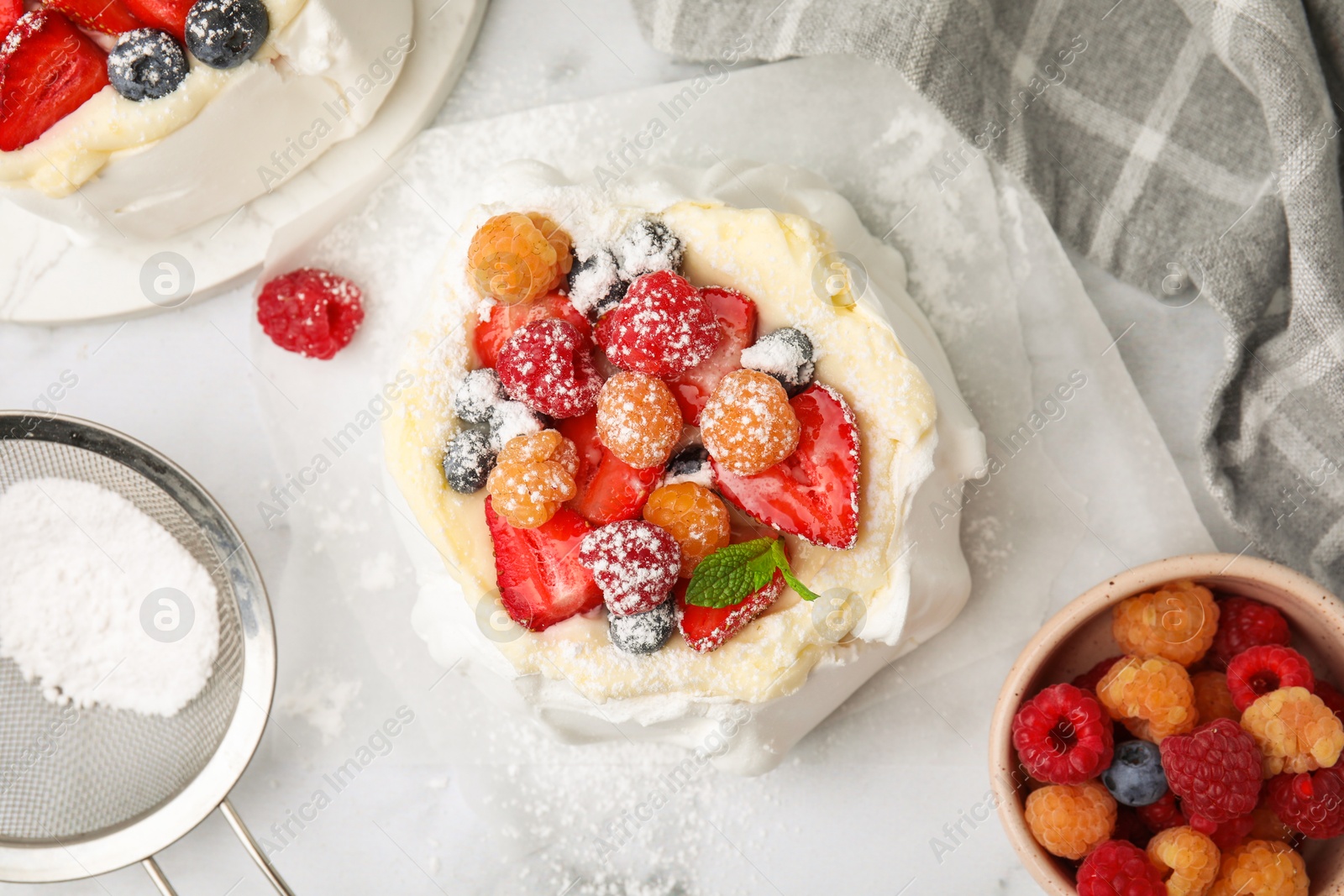 Photo of Pavlova cake (meringue dessert) with whipped cream, fresh berries, powdered sugar and mint on table, flat lay