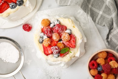 Photo of Pavlova cake (meringue dessert) with whipped cream, fresh berries, powdered sugar and mint on table, flat lay