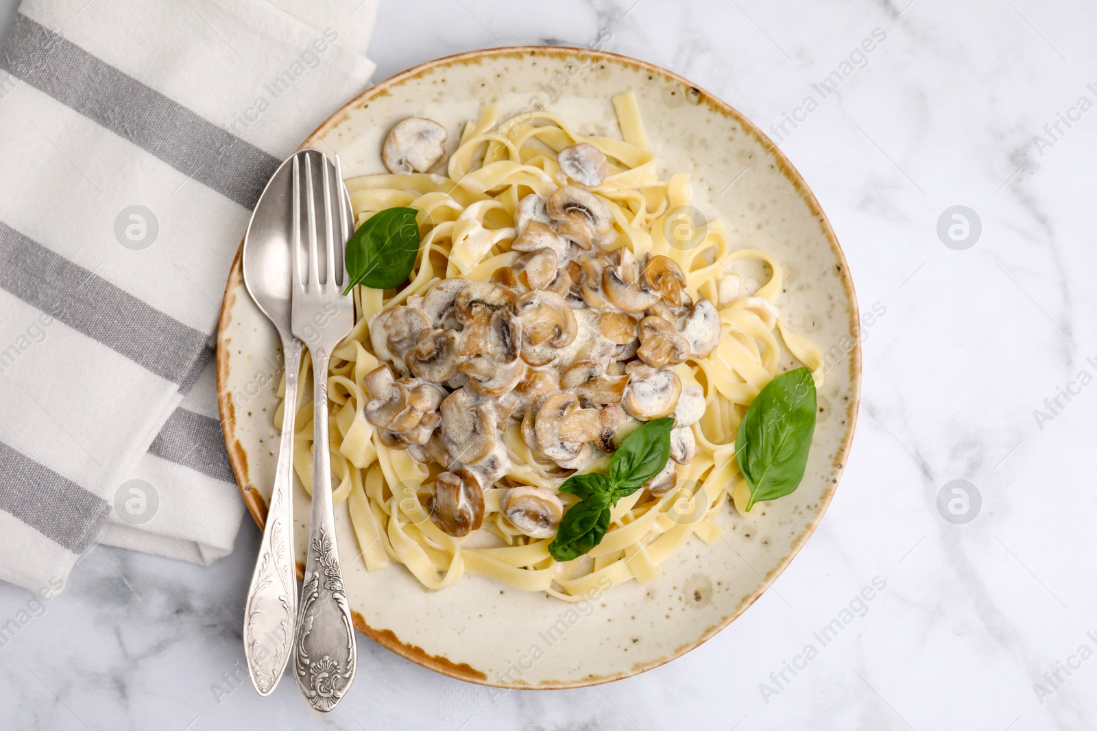 Photo of Delicious pasta with mushrooms and basil served on white marble table, top view