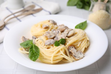 Photo of Delicious pasta with mushrooms and basil on white tiled table, closeup