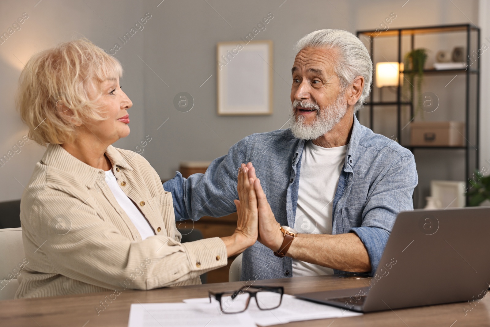 Photo of Pension savings. Senior couple planning budget at wooden table indoors