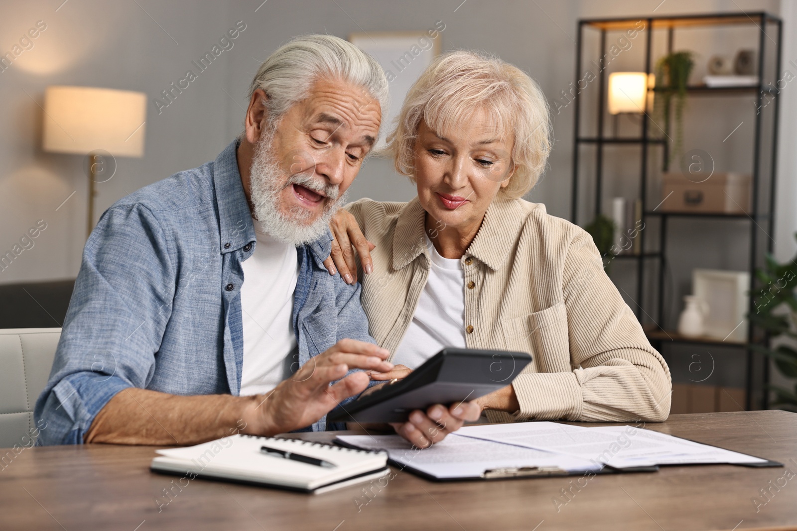 Photo of Pension savings. Senior couple planning budget at wooden table indoors