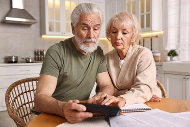 Photo of Pension savings. Senior couple planning budget at wooden table indoors