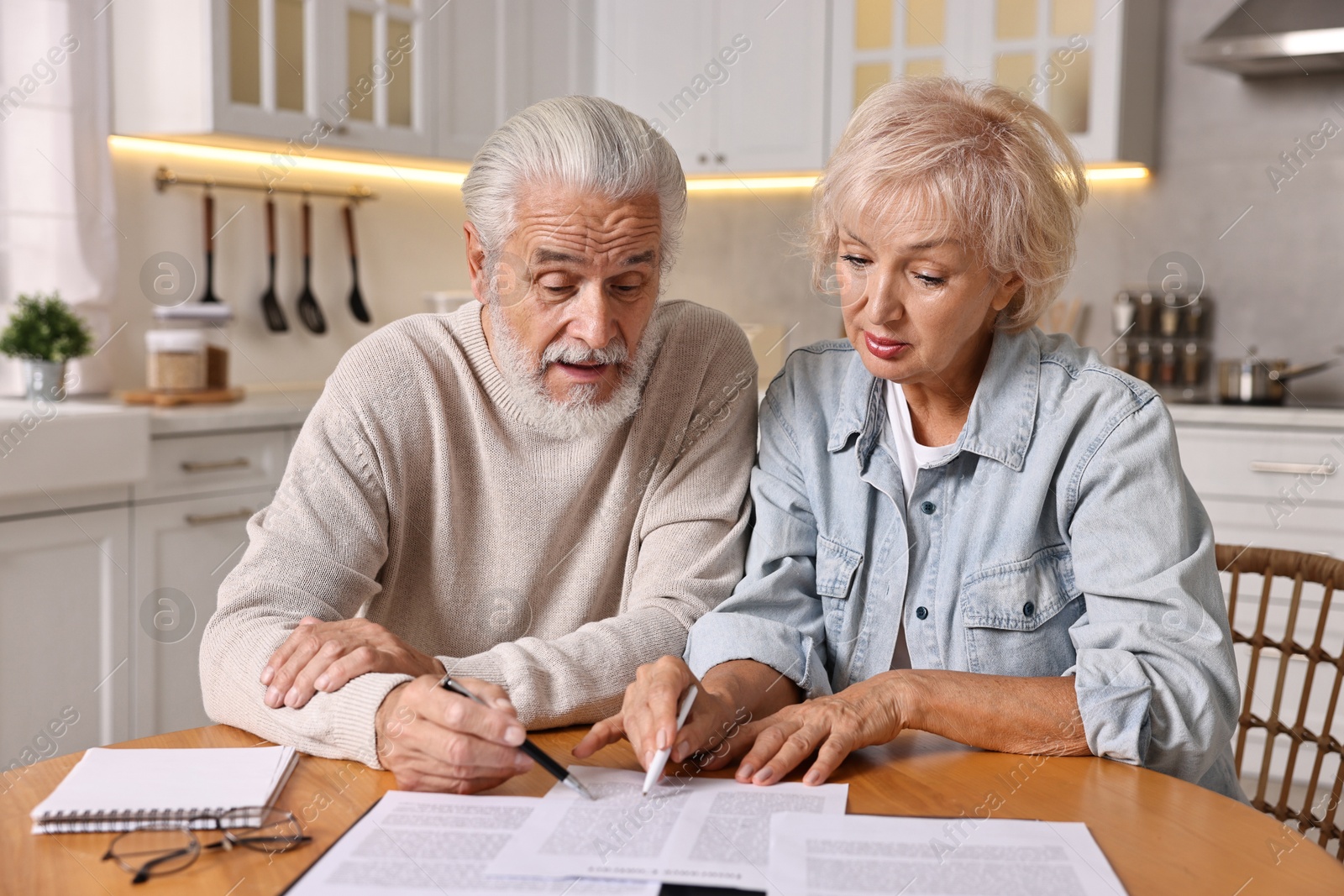 Photo of Pension savings. Senior couple planning budget at wooden table indoors