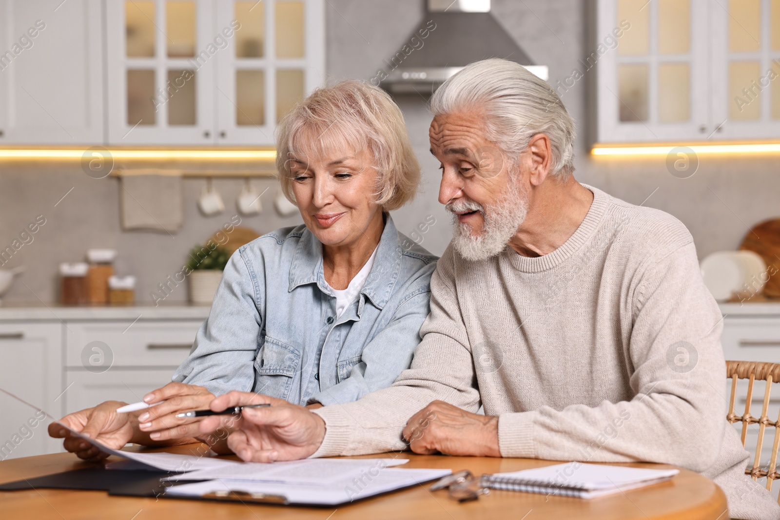 Photo of Pension savings. Senior couple planning budget at wooden table indoors