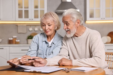 Pension savings. Senior couple planning budget at wooden table indoors