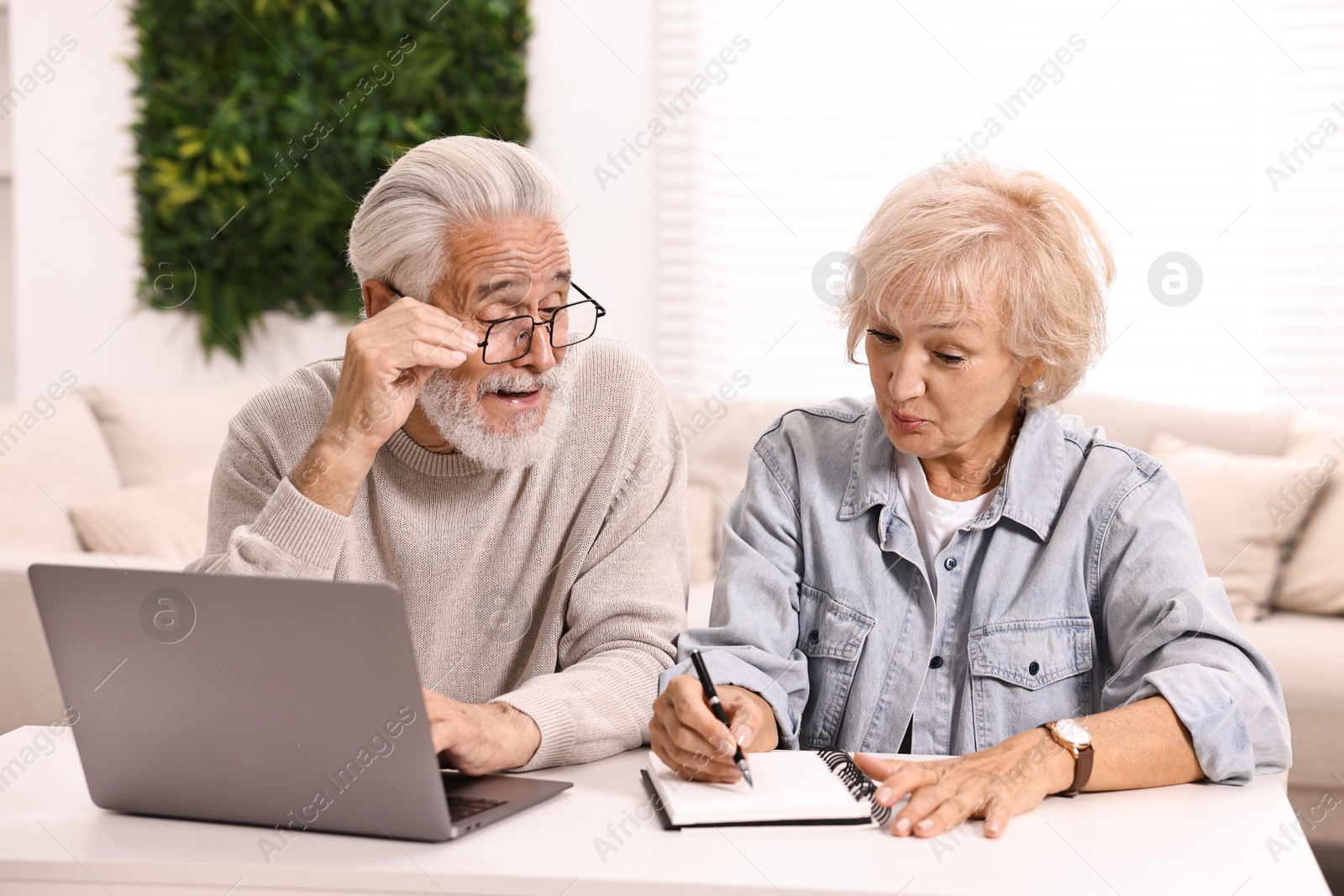 Photo of Pension savings. Senior couple planning budget at white table indoors