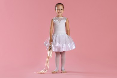 Photo of Little ballerina with pointe shoes on pink background