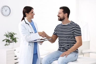 Healthcare worker shaking hands with patient in hospital