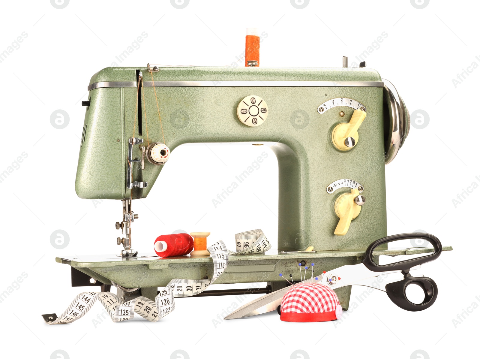 Photo of Sewing machine, measuring tape, scissors, pincushion and spools of threads isolated on white