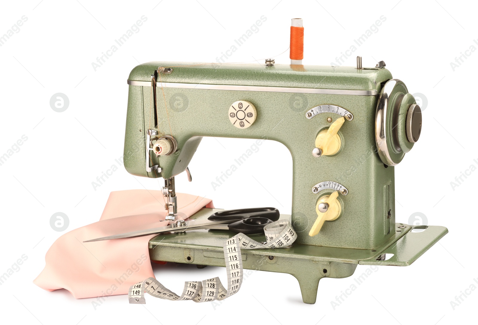 Photo of Sewing machine with pink fabric, measuring tape, scissors and spool of thread isolated on white