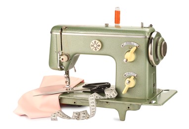 Photo of Sewing machine with pink fabric, measuring tape, scissors and spool of thread isolated on white