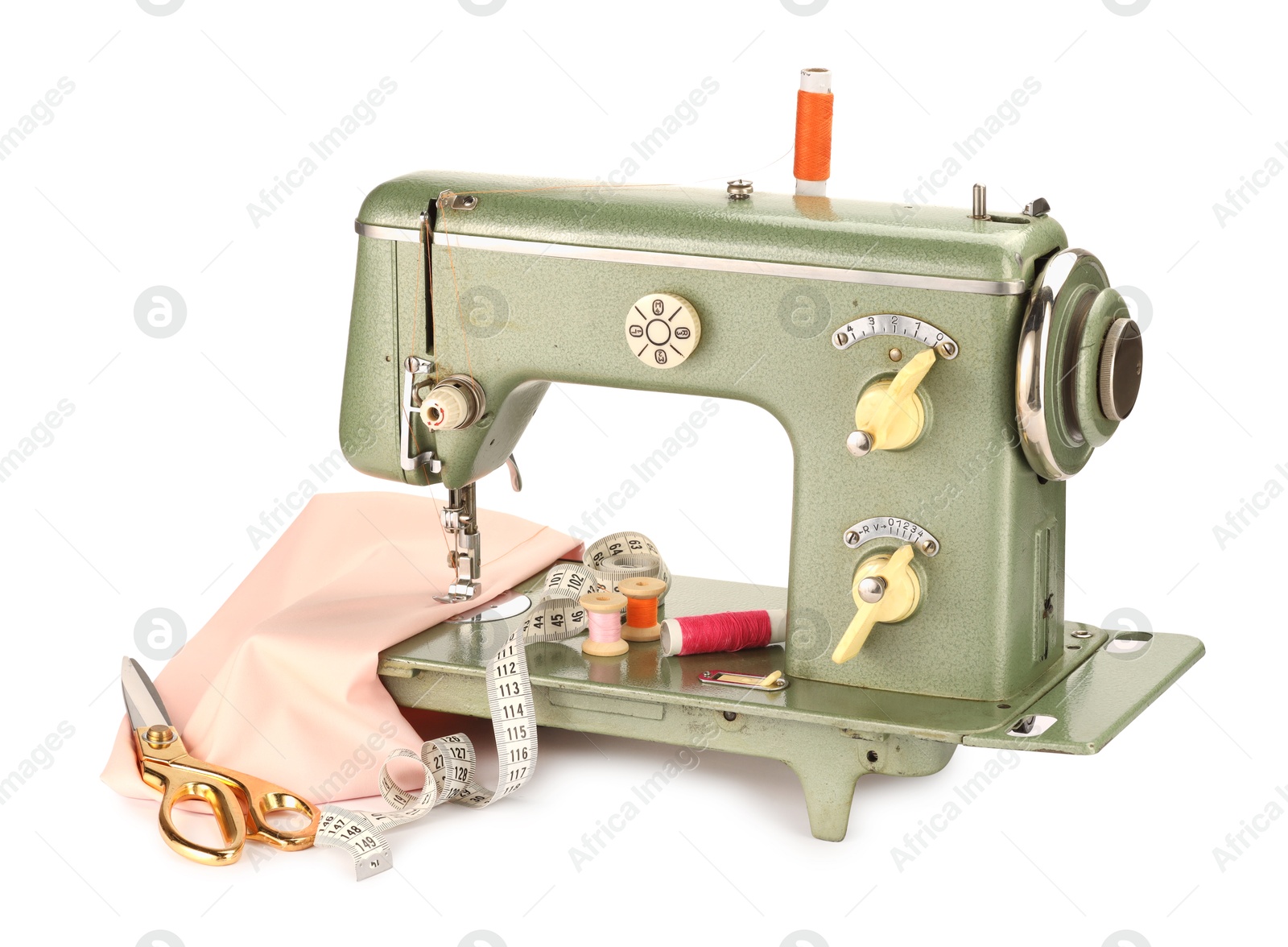 Photo of Sewing machine with pink fabric, measuring tape, scissors and spools of threads isolated on white