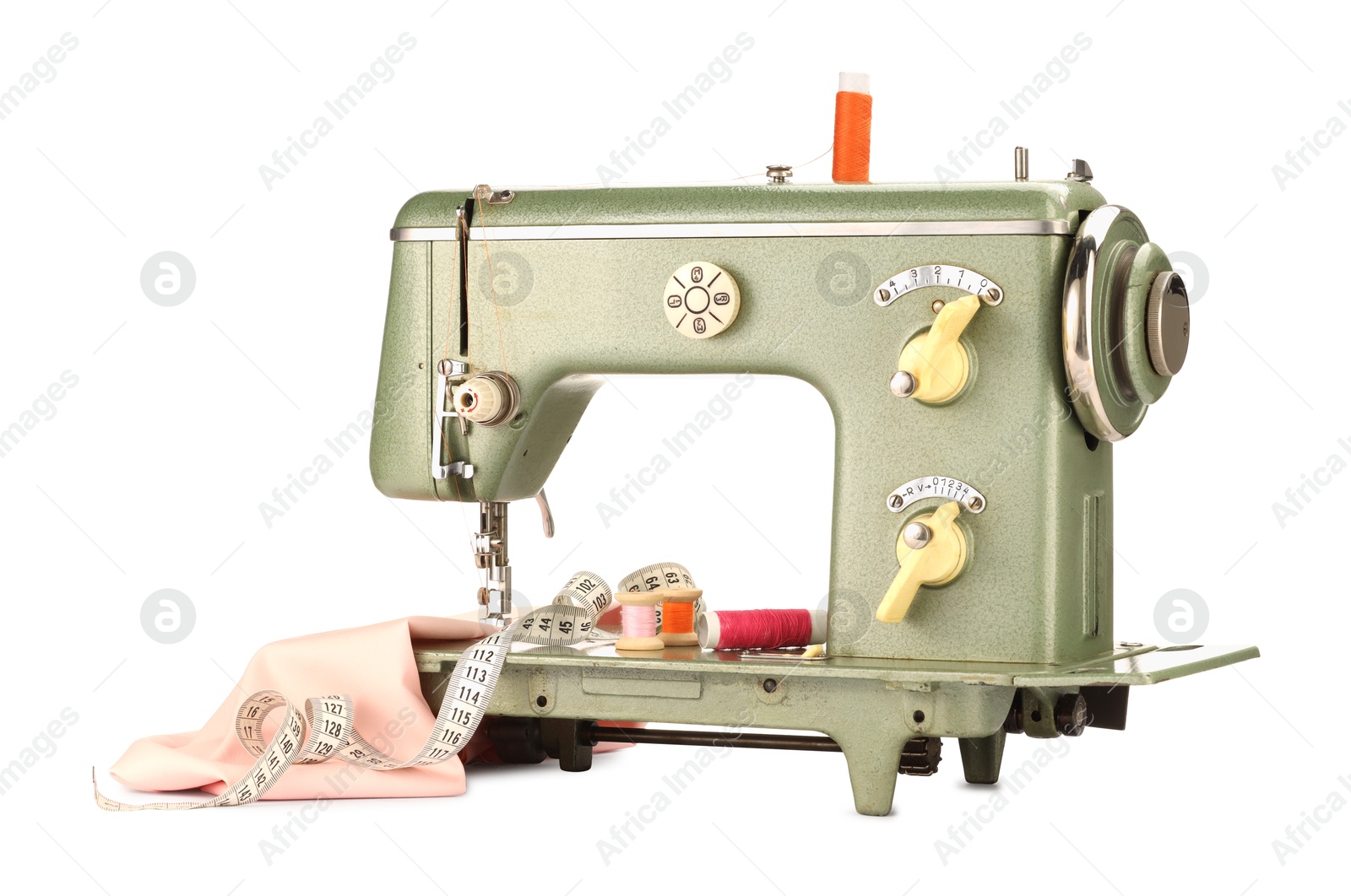 Photo of Sewing machine with pink fabric, measuring tape and spools of threads isolated on white