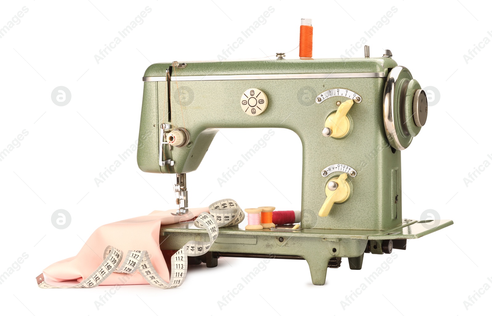 Photo of Sewing machine with pink fabric, measuring tape and spools of threads isolated on white