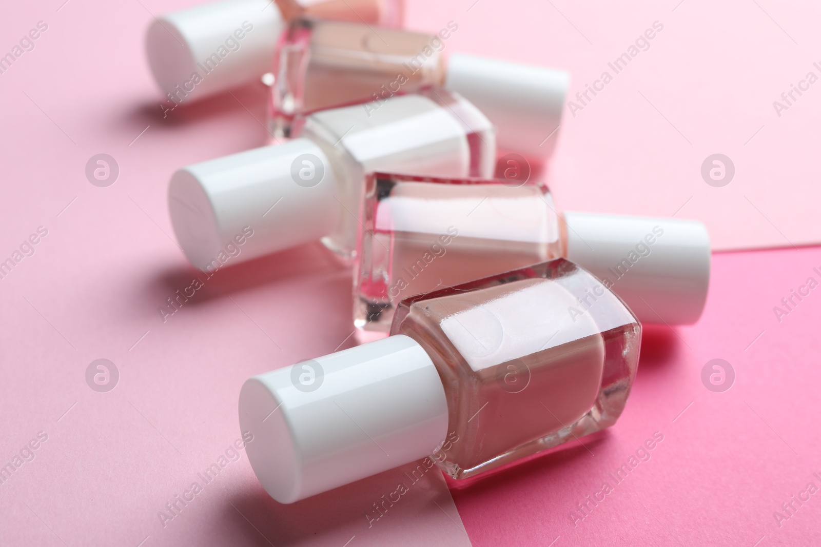 Photo of Nail polishes in bottles on color background, closeup