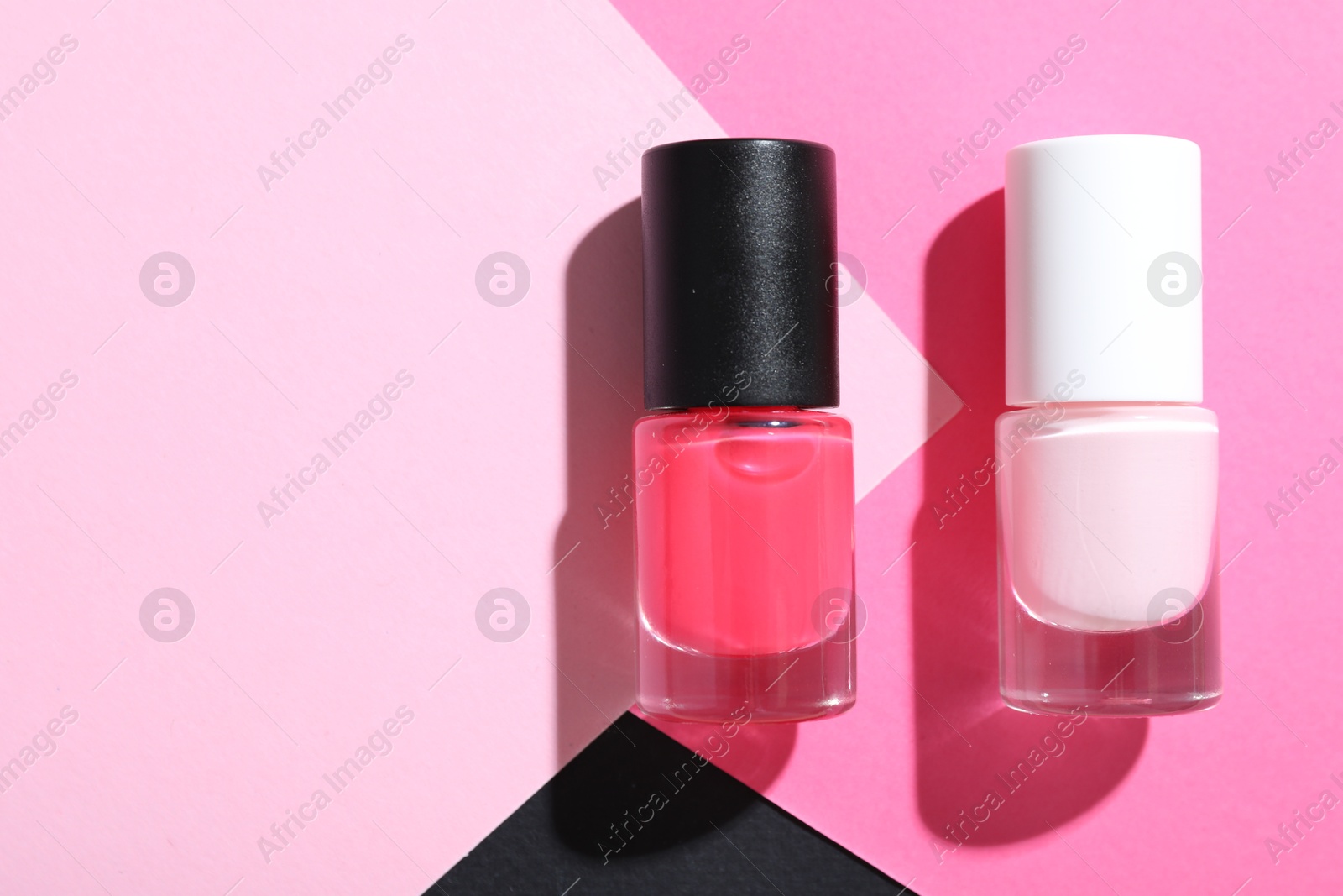 Photo of Nail polishes in bottles on color background, flat lay. Space for text