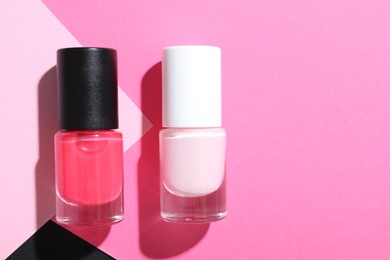 Photo of Nail polishes in bottles on color background, flat lay. Space for text