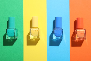 Photo of Nail polishes in bottles on color background, flat lay