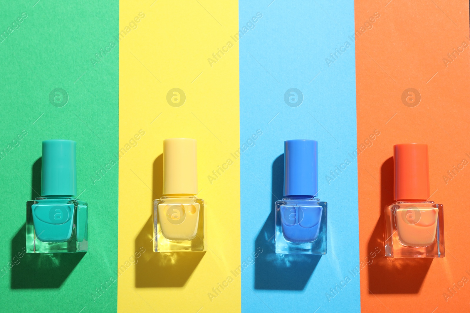 Photo of Nail polishes in bottles on color background, flat lay. Space for text